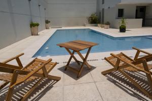 a picnic table and two chairs next to a swimming pool at Complejo Solares in Alta Gracia