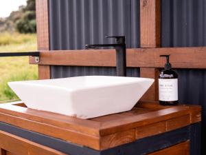un lavandino bianco e una bottiglia su un bancone in legno di Unique Glamping Experience & Romantic Dome with Nature Escape and River a Jaguas