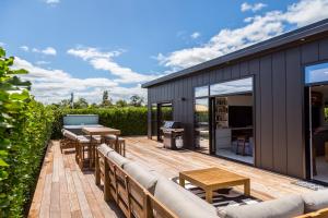 a deck with a couch and tables on a house at Sotally Tober Retreat in Martinborough 