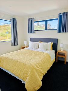 a bedroom with a large bed and two windows at New Built Gem in Hillcrest in Hamilton
