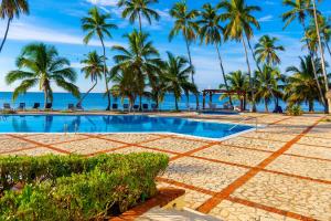 una piscina con palme sulla spiaggia di OCEANPARADISE to you ALBATRO l Y ll a Juan Dolio
