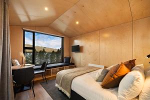 a bedroom with a bed and a desk and a window at The Huts at Lakes Edge in Lake Tekapo