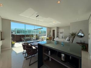 a large kitchen and living room with a dining table at QE01- Studio| Jacuzzi Aquecida| Piscina| Churrasq. in Cabeçudas