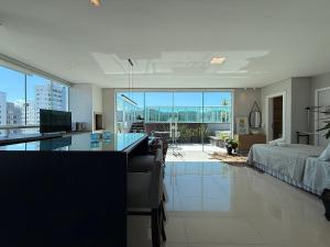 a large living room with a desk and a bed at QE01- Studio| Jacuzzi Aquecida| Piscina| Churrasq. in Cabeçudas
