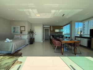 a bedroom with a bed and a table and a kitchen at QE01- Studio| Jacuzzi Aquecida| Piscina| Churrasq. in Cabeçudas +26 photos