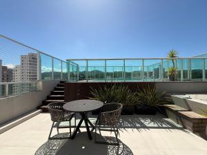a patio with a table and chairs on a balcony at QE01- Studio| Jacuzzi Aquecida| Piscina| Churrasq. in Cabeçudas