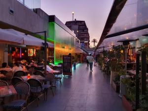 a man walking down a sidewalk next to a restaurant at Departamento con AC Ñuñoa in Santiago