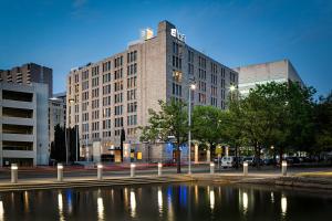 a large building with a pond in front of it at Aloft Dallas Downtown in Dallas