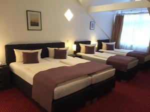 ein Hotelzimmer mit drei Betten in einem Zimmer in der Unterkunft Wincent Hotel GmbH in Sinsheim + 30 Fotos