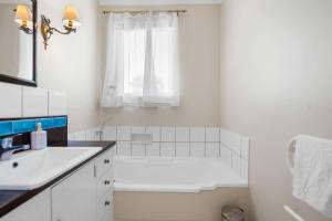a white bathroom with a tub and a sink at Stunning Lake Views & Hospital Location in Hamilton +13 photos