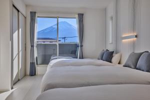 a room with three beds with a view of a mountain at MIYA HOUSE Funatsu C in Fujikawaguchiko