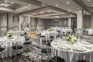 a banquet hall with white tables and chairs with flowers at Renaissance Boston Patriot Place Hotel in Foxborough +40 photos