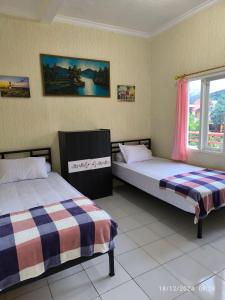 a bedroom with two beds and a window at Sierra Homestay 3 Bedrooms in Ngadipuro +11 photos