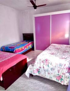 two beds in a room with purple and pink at Casa Grande Com Churrasqueira E Garagem in São Pedro da Aldeia +7 photos
