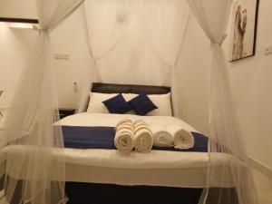 a bedroom with a canopy bed with towels on it at The Moose Weligama in Weligama