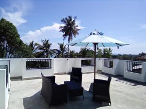 a patio with a table and chairs and an umbrella at The Moose Weligama in Weligama