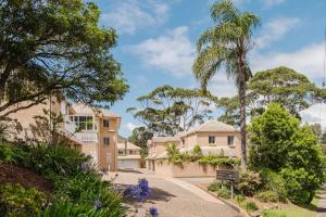 a house with a palm tree and a driveway at Sunset Poolside - Stay 3, Pay 2 - Spring Specials! in Mollymook