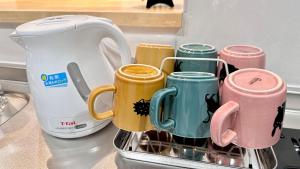 a group of coffee mugs in a rack on a counter at Ansou house 大阪ドーム in Osaka