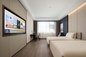 a hotel room with two beds and a flat screen tv at Atour X Hotel Ningbo Zhenhaizhuang Avenue in Ningbo