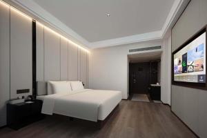 a bedroom with a white bed and a flat screen tv at Atour X Hotel Ningbo Zhenhaizhuang Avenue in Ningbo