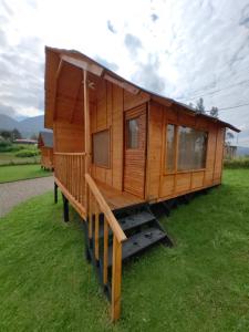 a wooden cabin with a large deck on the grass at Cabañas El Condominio in Guatavita
