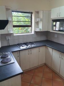 eine Küche mit weißen Schränken, einem Herd und einem Fenster in der Unterkunft 36 Steps to Beach Sand in Gqeberha