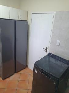 eine Küche mit einem Kühlschrank und einer schwarzen Mikrowelle in der Unterkunft 36 Steps to Beach Sand in Gqeberha