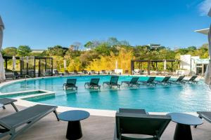 a large swimming pool with chairs and tables at Modern 1-Bedroom Apt in Núcleo Sabana Tower in San José
