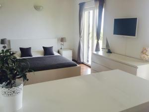 a white bedroom with a bed and a window at Apartments Aman in Makarska