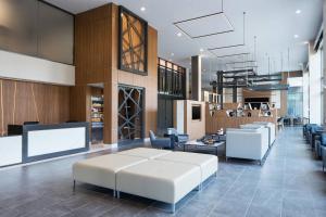 a hotel lobby with a white couch and chairs at AC Hotel by Marriott Louisville Downtown in Louisville