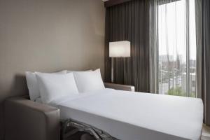 a white bed in a hotel room with a window at AC Hotel by Marriott Louisville Downtown in Louisville