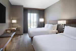 a hotel room with two beds and a desk at AC Hotel by Marriott Louisville Downtown in Louisville