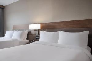 two beds in a hotel room with white pillows at AC Hotel by Marriott Louisville Downtown in Louisville