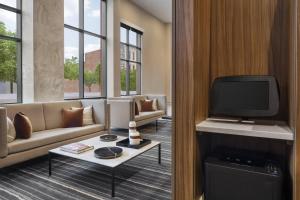a living room with a couch and a tv at AC Hotel by Marriott Louisville Downtown in Louisville