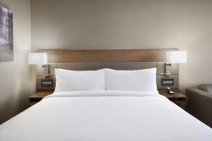 a bedroom with a large white bed with two lights at AC Hotel by Marriott Louisville Downtown in Louisville