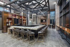 a bar in a restaurant with stools and a counter at AC Hotel by Marriott Louisville Downtown in Louisville