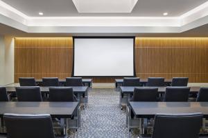 a conference room with tables and chairs and a white screen at AC Hotel by Marriott Louisville Downtown in Louisville