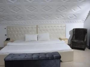 a bedroom with a large bed and a chair at Ambience Hotel and Suite - Deluxe in Abuja