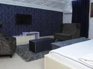 a bedroom with a bed and two chairs and a tv at Ambience Hotel and Suite - Deluxe in Abuja