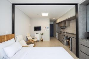 a bedroom with a large white bed and a kitchen at Grand Bleu Hotel & Residence in Incheon