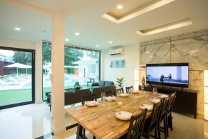 a large wooden table in a living room with a television at Big Alice Pool Villa Pattaya in Ban Hui Yai Muk