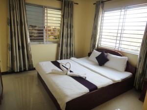 a bedroom with a bed with two white swans on it at Khemra I Guesthouse in Kampot