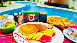 a plate of breakfast food on a table by a pool at 5th Avenue 3 people Balcony Apartment in Playa del Carmen +12 photos