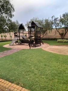 a park with two playground equipment in the grass at Quiet, Very Specious Apartment In Dainfern in Johannesburg