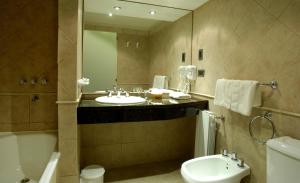 a bathroom with two sinks and a tub and a toilet at Hotel Quijote in El Calafate