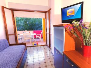 un salon avec un canapé, une télévision et une table dans l'établissement Residence Carina, à Bibione