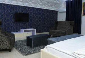 a bedroom with a bed and a chair and a tv at Ambience Hotel Magodo - Deluxe in Lagos