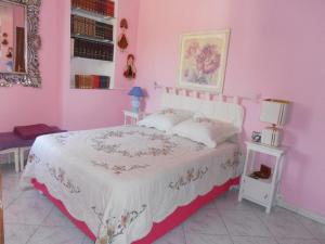 Villa ClaireLou في بيرتويس: غرفة نوم وردية مع سرير ولحاف ابيض