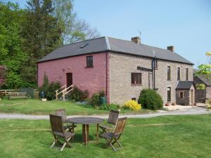 a table and chairs in front of a brick building at Brynderwen Barn in Llangorse