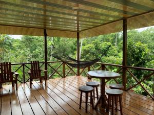 a porch with chairs and tables and a hammock at Villa with primary forest view in Drake